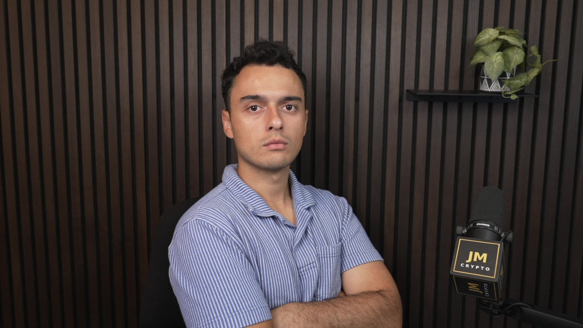 Jesus Martinez with his arms crossed beside a JM Crypto microphone